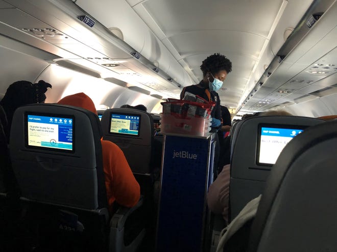 A JetBlue Airways flight attendant serves passengers snacks on a flight from New York to Cancun, Mexico. JetBlue has among the most generous free snack offerings during the pandemic.
