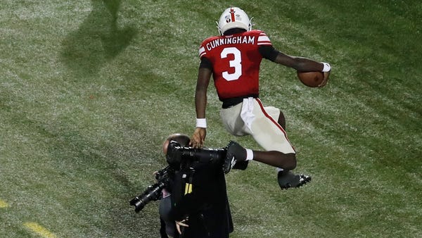 Louisville's Malik Cunningham leaps over a photogr