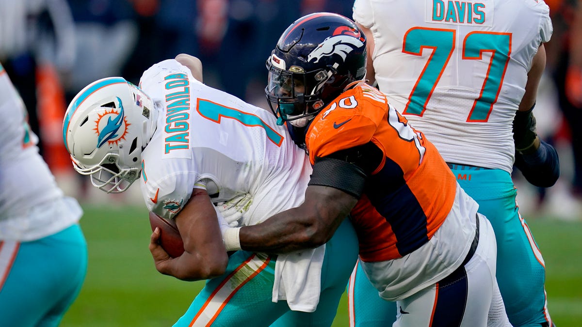 Denver Broncos defensive end DeShawn Williams (90) sacks Miami Dolphins quarterback Tua Tagovailoa (1) during the second half of an NFL football game, Sunday, Nov. 22, 2020, in Denver.