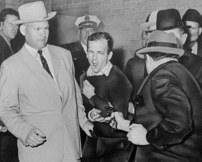 Lee Harvey Oswald, assassin of President John F. Kennedy, reacts as Dallas night club owner Jack Ruby, foreground, shoots him from point-blank range in a corridor of Dallas police headquarters, Nov. 24, 1963.