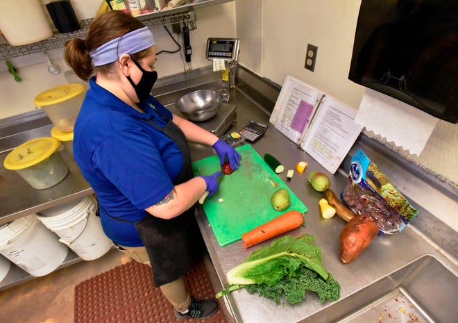 Occasionally glancing at a three-ring binder recipe book, Sophie Berman-Woodward, an animal nutrition technician, chops vegetables and fruits to feed the primates on Nov. 16 at the Jacksonville Zoo and Gardens.