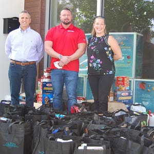 Alton Town Center and Adopt-A-Family of the Palm Beaches teamed to host a food drive this month to aid families in need during Thanksgiving. From left are Alton Town Center Property Manager Joe Ragonese; Revive Clinical Manager and Director of Sales Ben Handy; and Adopt-A-Family Director Emily Gorman.