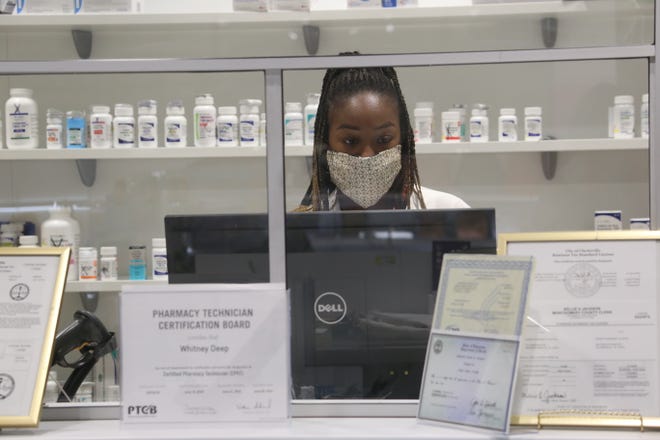 Pharmacist T'Bony Jewell works behind the counter at her local Clarksville pharmacy, Zoren Pharmacy & Gifts, on Nov. 19, 2020.
