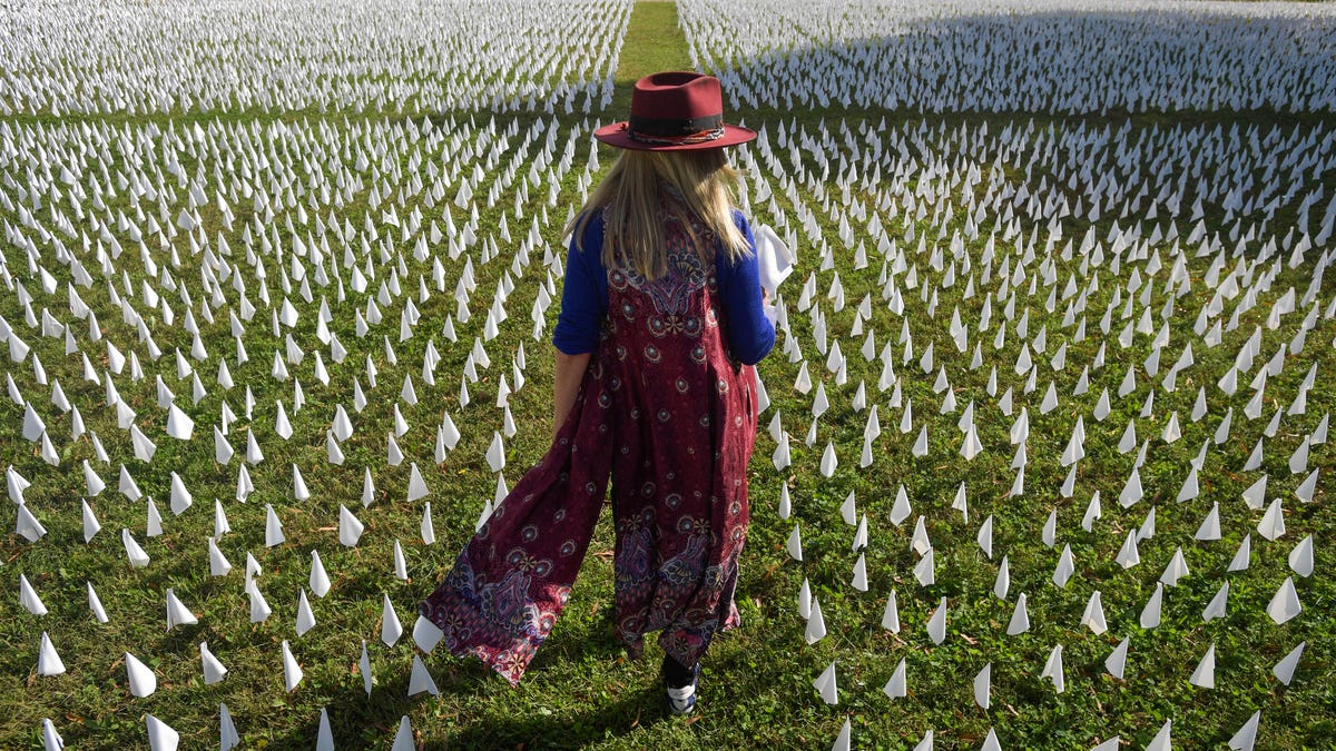 Artist Suzanne Firstenberg walks through an installation on the DC Armory Parade Ground on Friday, October 23, 2020 in Washington, DC. Titled "IN AMERICA: How Could This Happen," each flag represents a life lost to COVID-19 in the United States. At the time of the installation, the number of flags totaled just under 225,000.