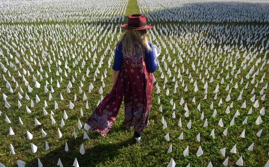 Artist Suzanne Firstenberg walks through an installation on the D.C. Armory Parade Ground titled "IN AMERICA: How Could This Happen," where each flag represents a life lost to COVID-19 in the USA.