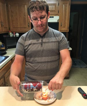 Michael Ashcraft of Wix and Match Candles heats a bottle in preparation of making it into a candle vessel. A portion of proceeds from candles sold goes to the Nisonger Center at Ohio State University to help those with autism, like him.