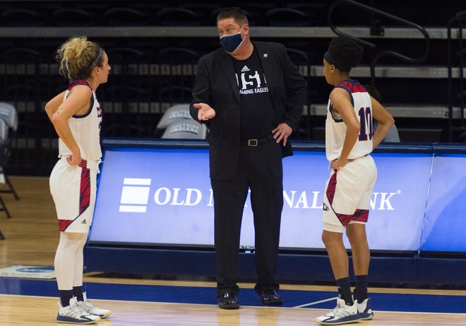 USI’s Head Coach Rick Stein gives direction to USI’s Emma Dehart (30) and Ashley Hunter (10) as the University of Southern Indiana Screaming Eagles play the Rockhurst Hawks at Screaming Eagles Arena in Evansville, Ind., Friday afternoon, Nov. 27, 2020. 