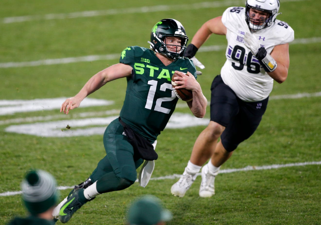 Michigan State quarterback Rocky Lombardi, left, runs for a first down against Northwestern's Trevor Kent during the fourth quarter.