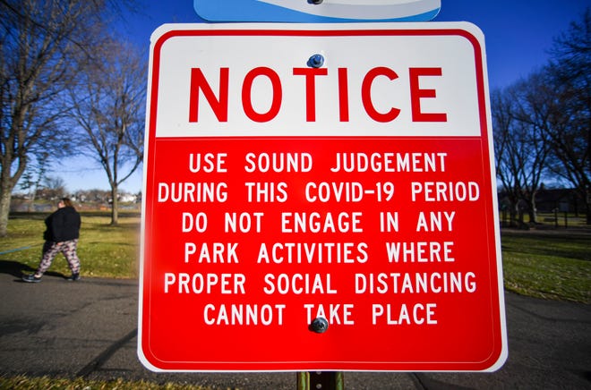 A sign highlighting COVID-19 precautions is posted near Eastman Park Monday, Nov. 30, 2020, in St. Cloud.  
