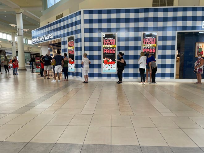 Black Friday shoppers stand in line outside the Bath and Body Works store at Treasure Coast Square in Jensen Beach, Fla., on Friday, Nov. 27, 2020. Mall patrons are required to wear face coverings as the COVID-19 pandemic persists.