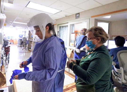 Deb Dalsing, nurse manager of the COVID-19 treatment unit at UW Health, assists nurse Ainsley Billesbach with her personal protective equipment Nov. 5 in Madison, Wis.