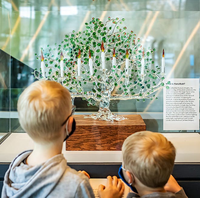 Siggy Meek, 6, and Lane Meek, 4, inspect the newly created Menora Tree of Life, in celebration of Hanukkah, at the Corning Museum of Glass.