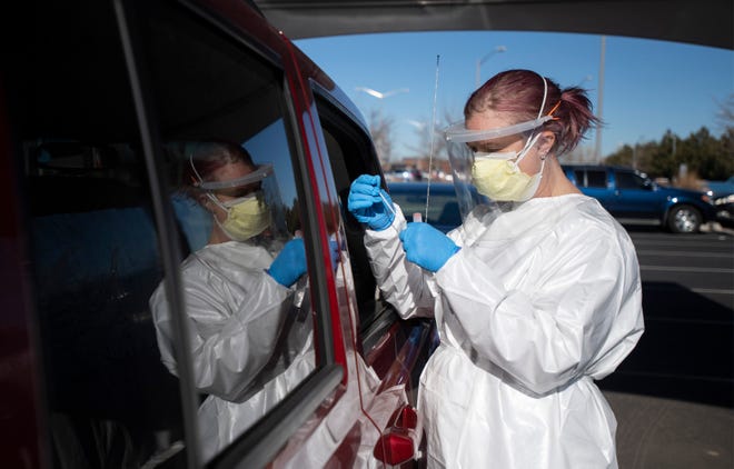 A healthcare worker finishes testing a passenger at a Larimer County COVID-19 testing site at Colorado State University in Fort Collins, Colo. on Thursday, Dec. 3, 2020.