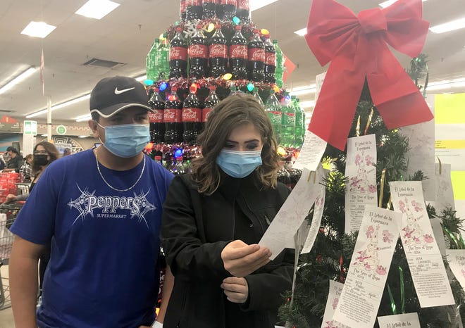 Andres Gonzales and Sierra Green pull a tag from the Tree of Hope at Peppers Supermarket. The two Peppers employees are planning to purchase a Christmas gift for a needy family member in Palomas, Chih. Mexico.
