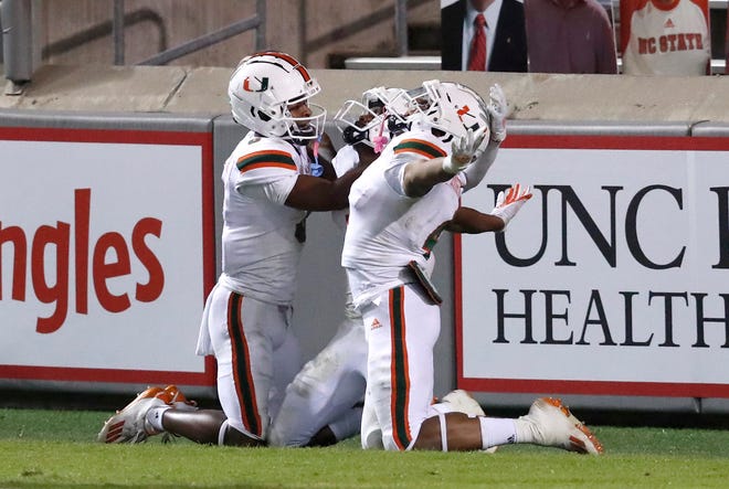 Miami’s Mark Pope, left, and Jaylan Knighton, right, celebrate with Mike Harley during a win this season at N.C. State.