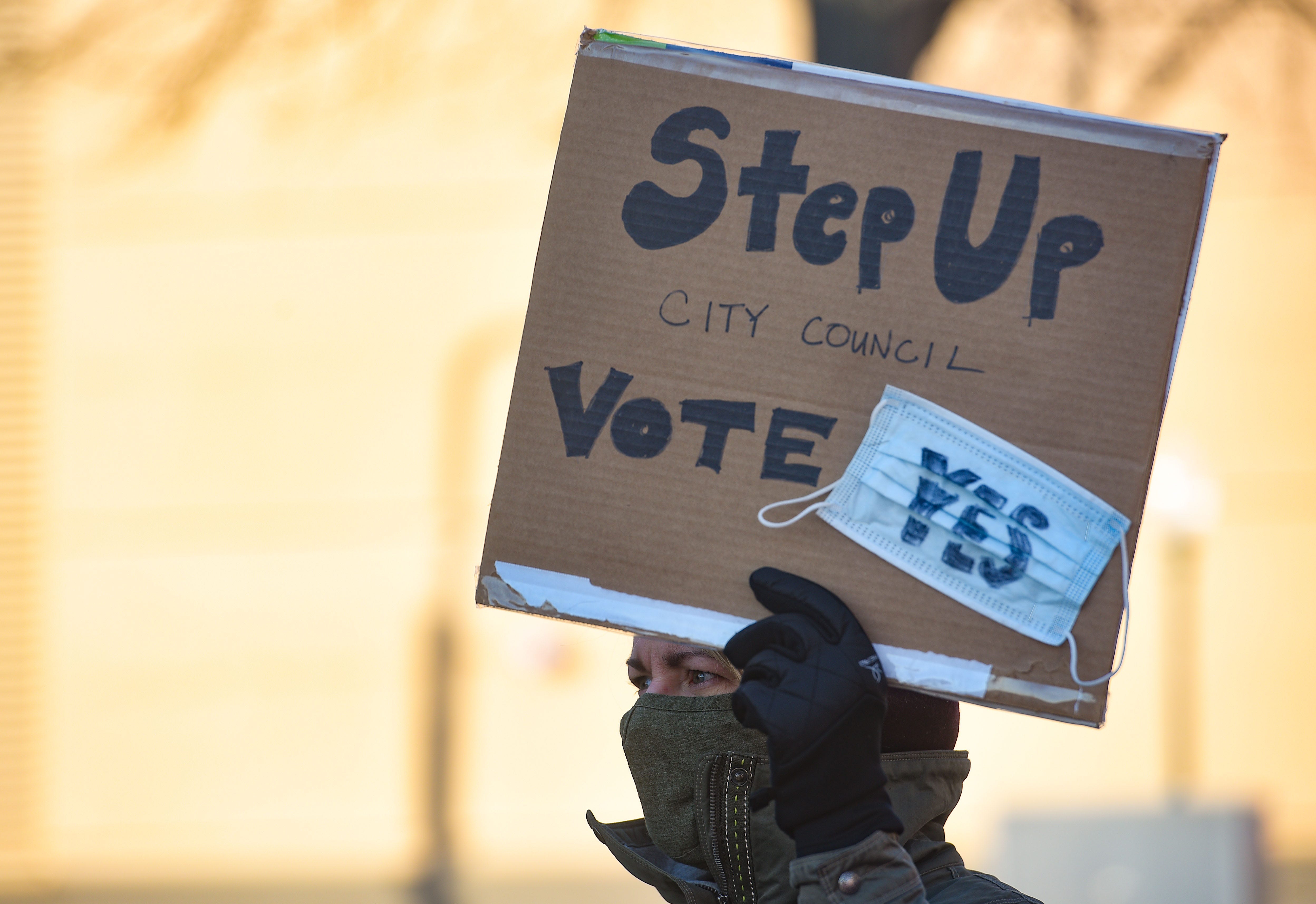 A demonstrator holds a sign demanding a mask mandate from the city council on Monday, November 16, outside Carnegie Town Hall in Sioux Falls.