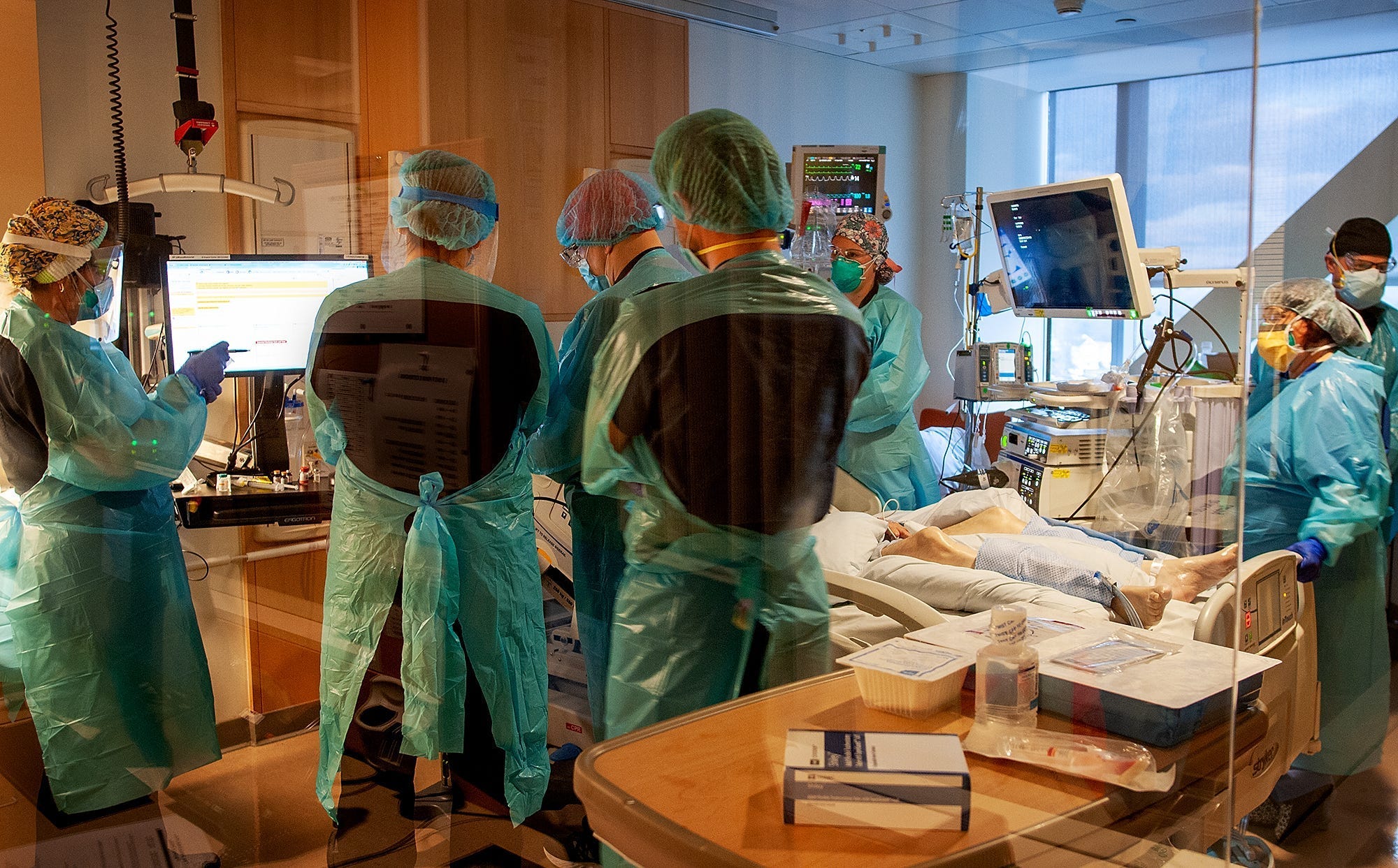 A team of health care workers on Nov. 18 perform a procedure on a patient with COVID-19 at UMass Memorial Medical Center. The group of nurses, doctors, and respiratory therapists work on a floor of negative-pressure rooms treating 18 patients with COVID-19 requiring an intensive care unit level of care.