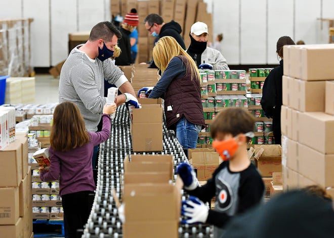 Volunteers work to pack holiday food boxes for the annual Give-A-Meal program during a family volunteering day at York County Food Bank's Emergency Food Hub on Haines Road in Springettsbury Township, Saturday, Dec. 5, 2020. Age limit restrictions were lifted for the day to allow younger children to experience being able to give back to those in need. Dawn J. Sagert photo