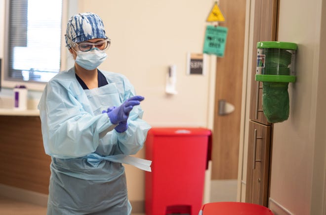 Nurse Amy Farley of Monument Health in Rapid City applies personal protective equipment before aiding COVID-19 patients in the intensive care unit. Hospital officials in South Dakota say rising COVID-19 cases are straining their ability to care for patients with the most severe symptoms.