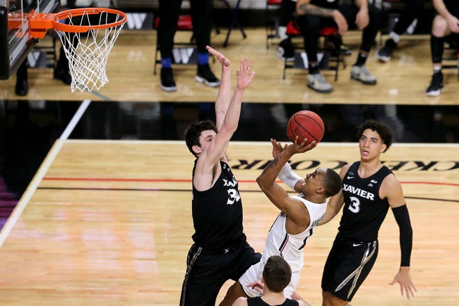 Cincinnati Bearcats guard Mika Adams-Woods (23) takes a shot in the lane as Xavier Musketeers forward Zach Freemantle (32) defends in the first half of the 88th Crosstown Shooutout NCAA college basketball game, Sunday, Dec. 6, 2020, at Fifth Third Arena in Cincinnati.