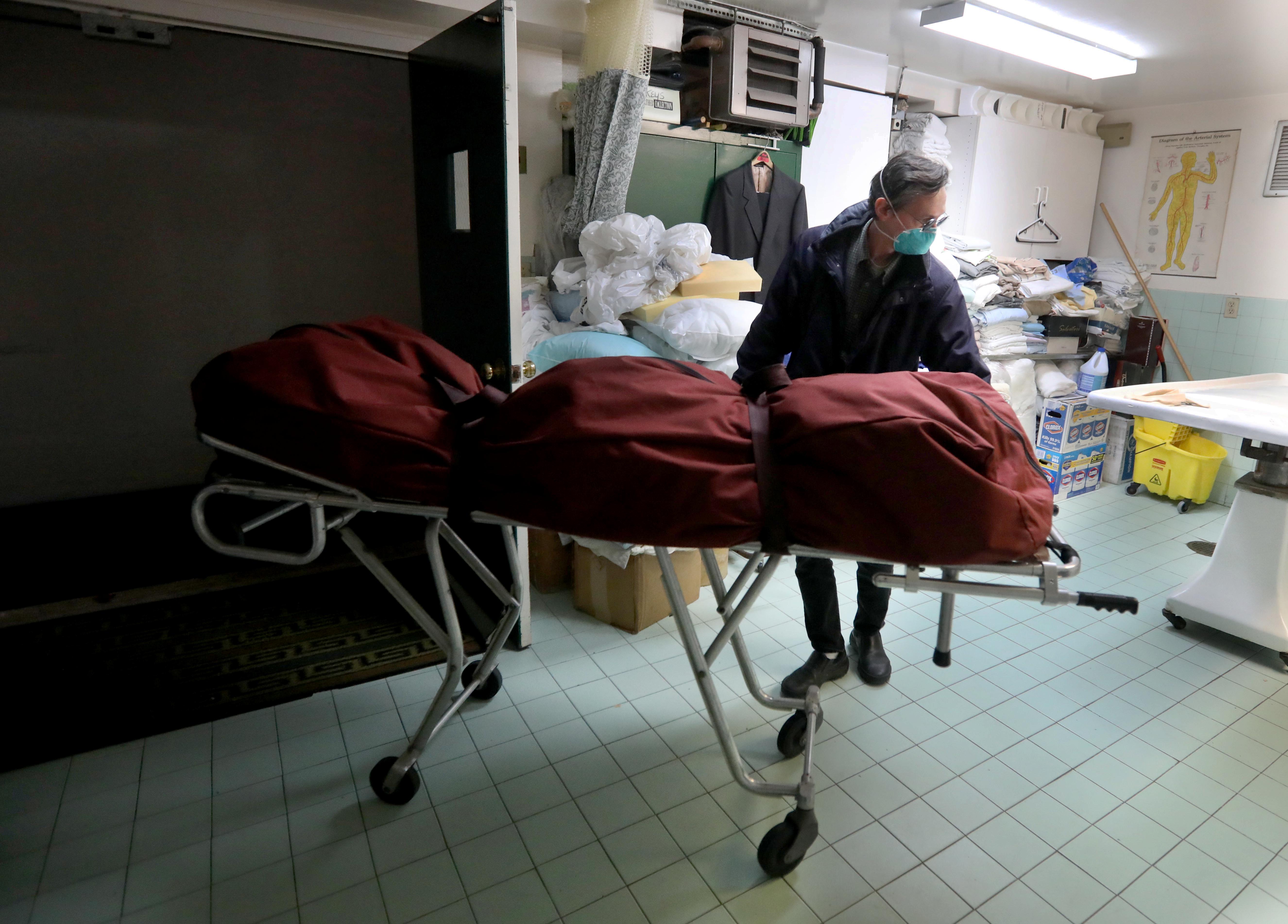 At the start of the COVID-19 pandemic, funeral directors went from handling four funerals a week to at least five burials or cremations daily. Here funeral director Mark Flower places a body that he just picked up from the New York City Medical Examiner's office in the prep room of his Yonkers funeral home.