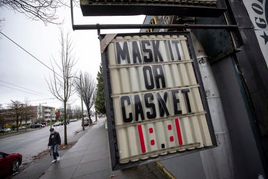 A sign regarding mask use to help curb the spread of COVID-19 hangs on Sunday outside a business in Vancouver, British Columbia.