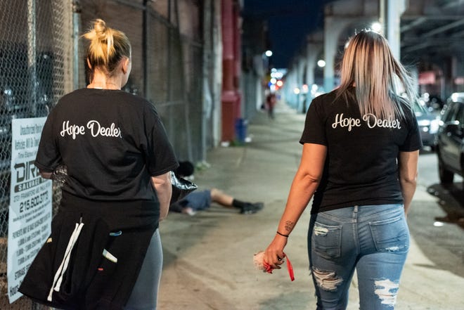 Maureen McGuire, left, and Megan Cohen, walk along Kensington Avenue, under the lights of the El tracks in the Kensington neighborhood of Philadelphia on Thursday, October 8, 2020.