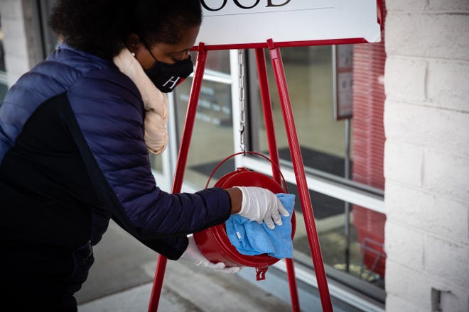 A Salvation Army volunteer sanitizes a kettle before starting to collect financial donations as part of the charitable organization's safety protocols during the pandemic.