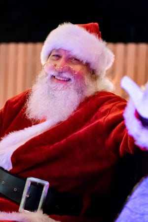Santa Claus waves to children and adults alike while asking their Christmas wishes from a safe social distance.
