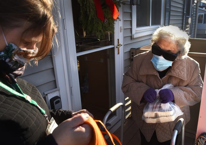Melissa Dixon of Southern Maine Agency on Aging's Meals on Wheels program hands Rose Cedrone, 96, her food that she depends on each week.