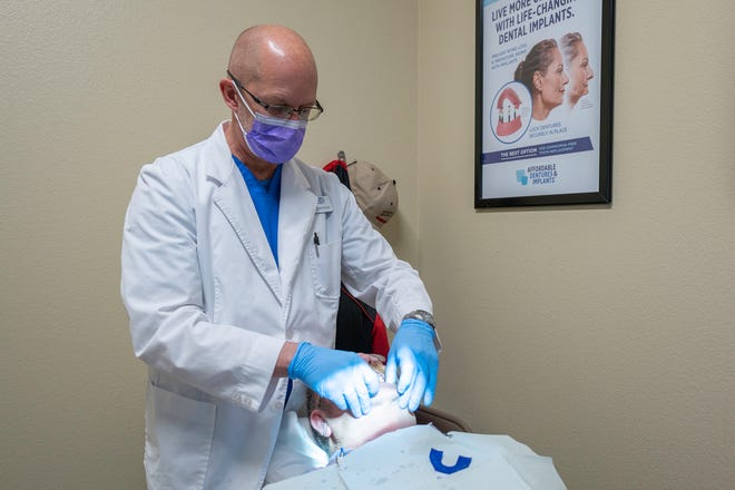 Dr. Curtis Broeker of Affordable Dentures and Implants fits Roger Powell with a new set of dentures on Tuesday December 8, 2020.