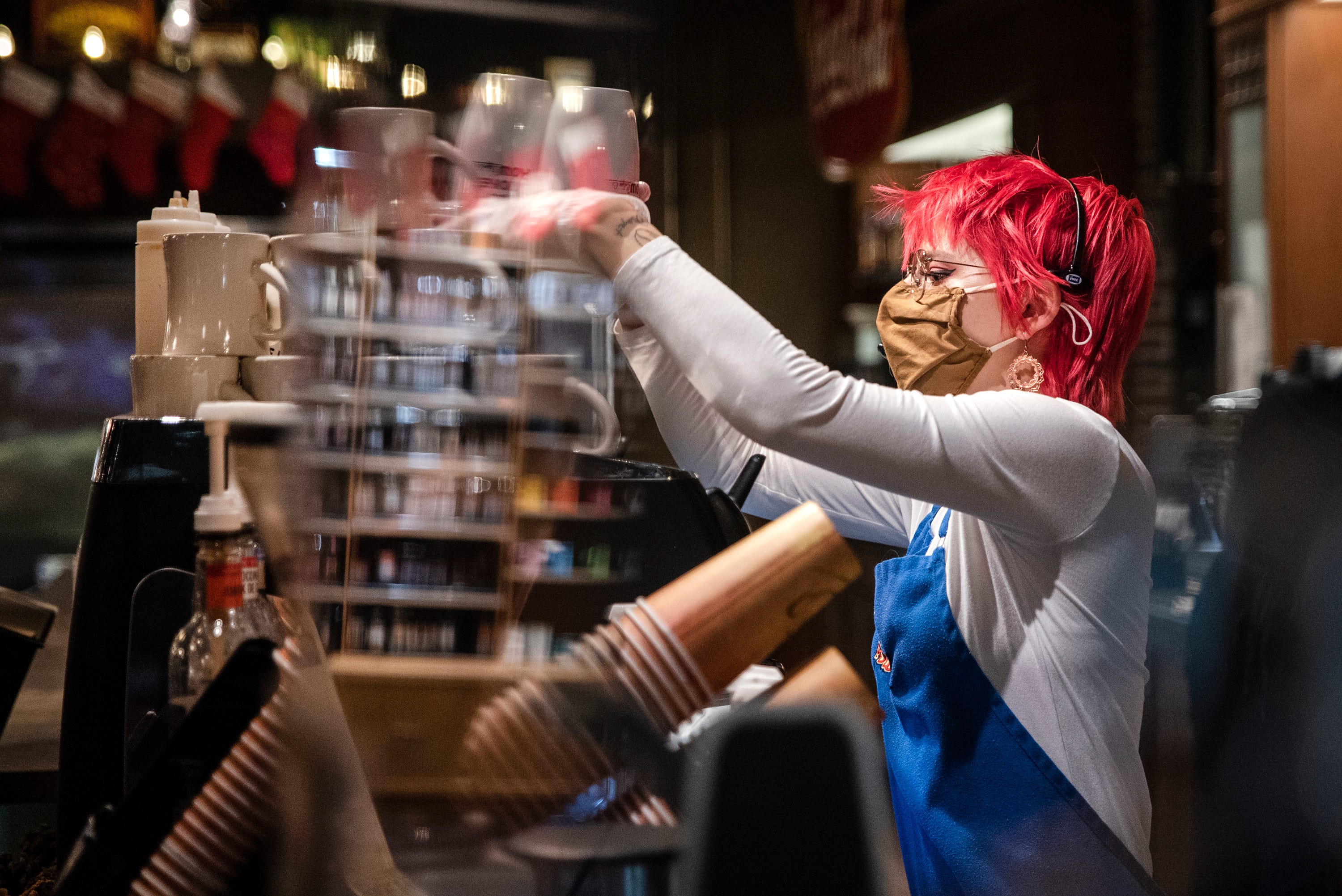 6:12 a.m.: Smokey Row shift manager Addison Connelly stacks mugs on Tuesday morning. Reinforcing mask requirements among customers in the cafe is a common occurrence, especially when ordering in-person, Connelly said.