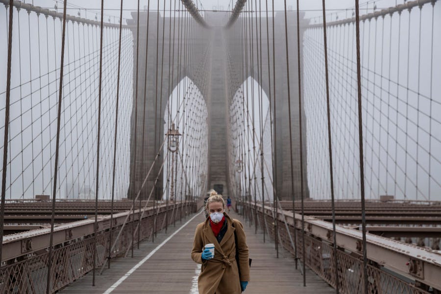 A woman wearing a mask walks the Brooklyn Bridge in the midst of the coronavirus (COVID-19) outbreak on March 20, 2020 in New York City. 