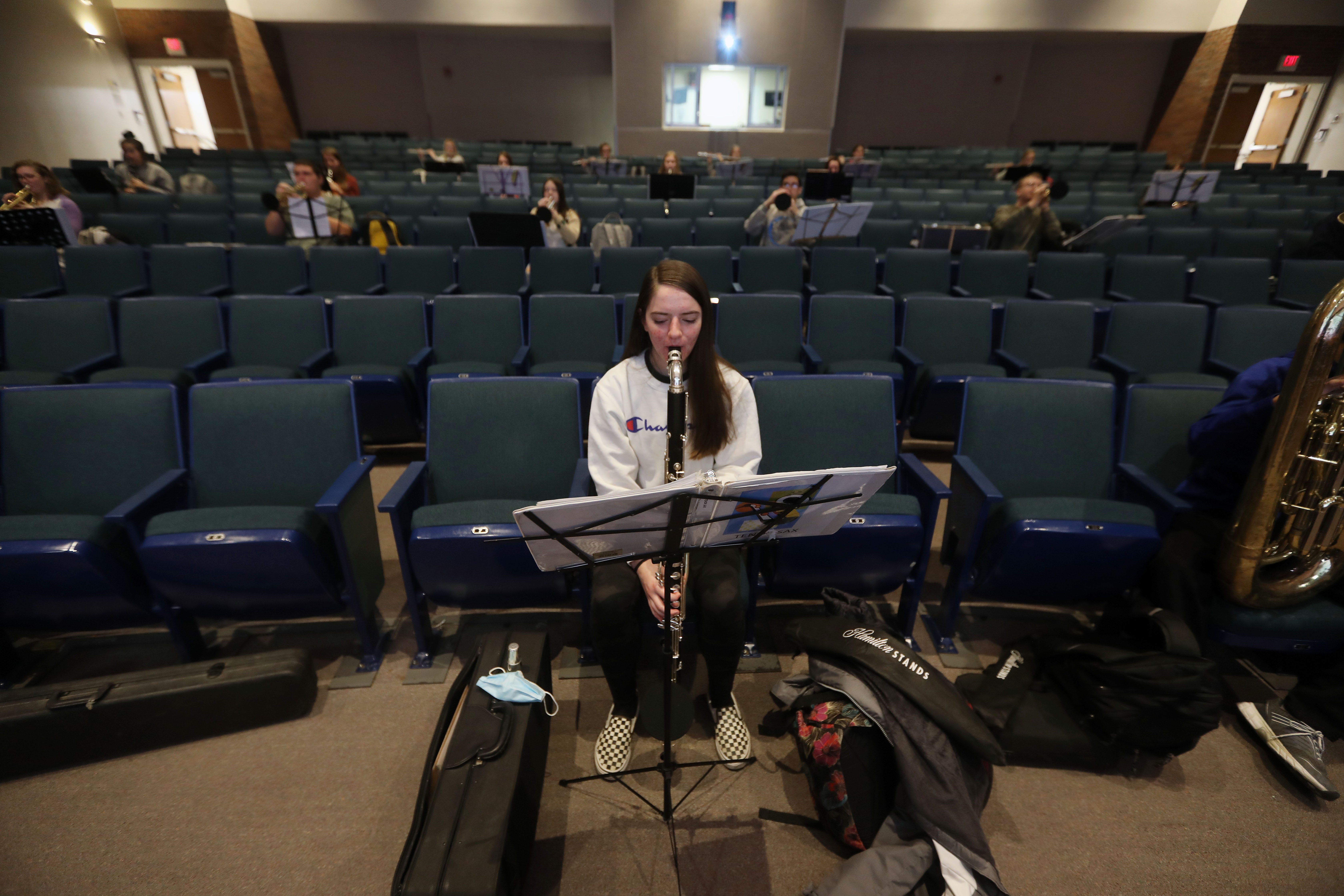 8:19 a.m. Kyra Garr, 15, is surrounded by empty chairs as she warms up by playing long tones on her bass clarinet during a socially distant rehearsal with her West Burlington High School bandmates Tuesday, Dec. 8, 2020, in West Burlington. 
Music filled the cavernous space designed to accommodate 300 people as 30 musicians played several holiday songs for their upcoming Christmas concert. 
"The hardest thing about the concert is you never know from one week to the next if a kid is going to go on quarantine, or if they are going to go to virtual or if they are not going to be there any more," said Mark Eveleth, the school's band director. 
Eveleth and vocal music instructor Annette Siebers started planing last fall for how to teach music in the era of COVID-19. The two developed a plan for rehearsals in the auditorium. 
No longer are students sharing music stands or music. Instead, each student provides their own to use during a socially distant practice.