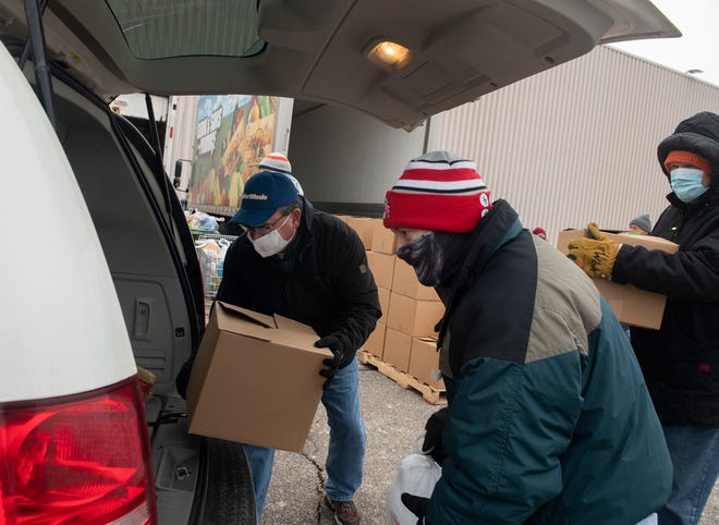 Volunteers distribute toys and food to those in need. Jim Antal, Todd Hurd and Pete Mahoney place boxes of goods in the back of a minivan.