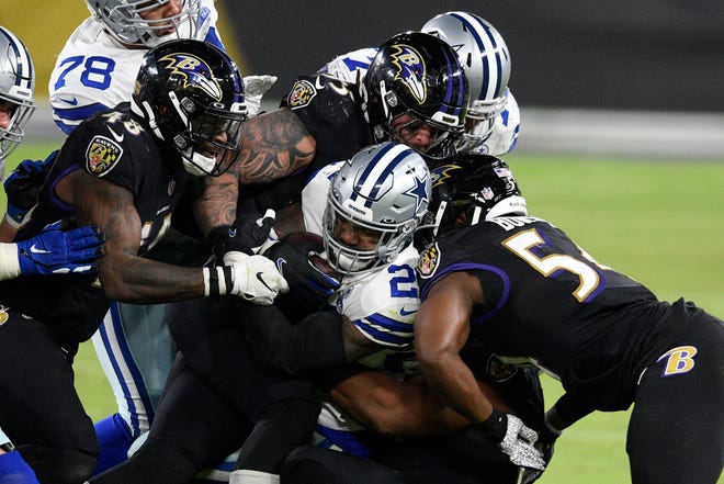 Dallas Cowboys running back Ezekiel Elliott, center, is brought down by a host of Baltimore Ravens defenders during the second half of an NFL football game, Tuesday, Dec. 8, 2020, in Baltimore.