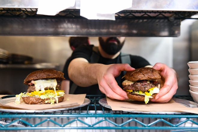 Conner McMahan plates two B&C Raclette Burgers on Monday, Jan. 13, 2020, at Bread and Circus Sandwich Kitchen in Sioux Falls.