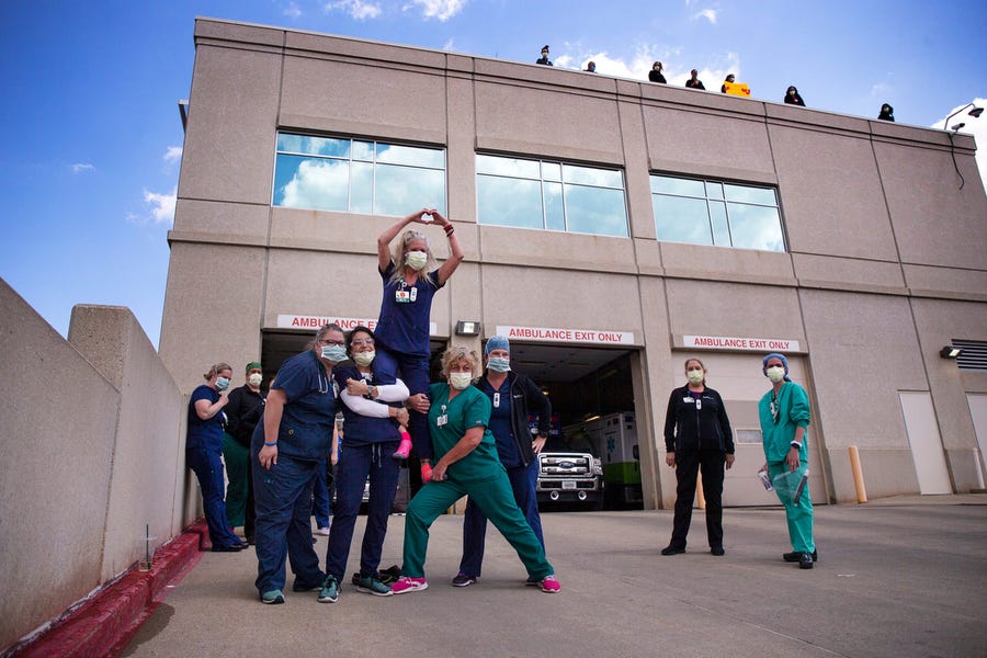 Fellow emergency room nurses hold up Cece Olsen on May 6 to watch a parade called an "appreciation loop" pass by MercyOne Medical Center in Des Moines, Iowa.