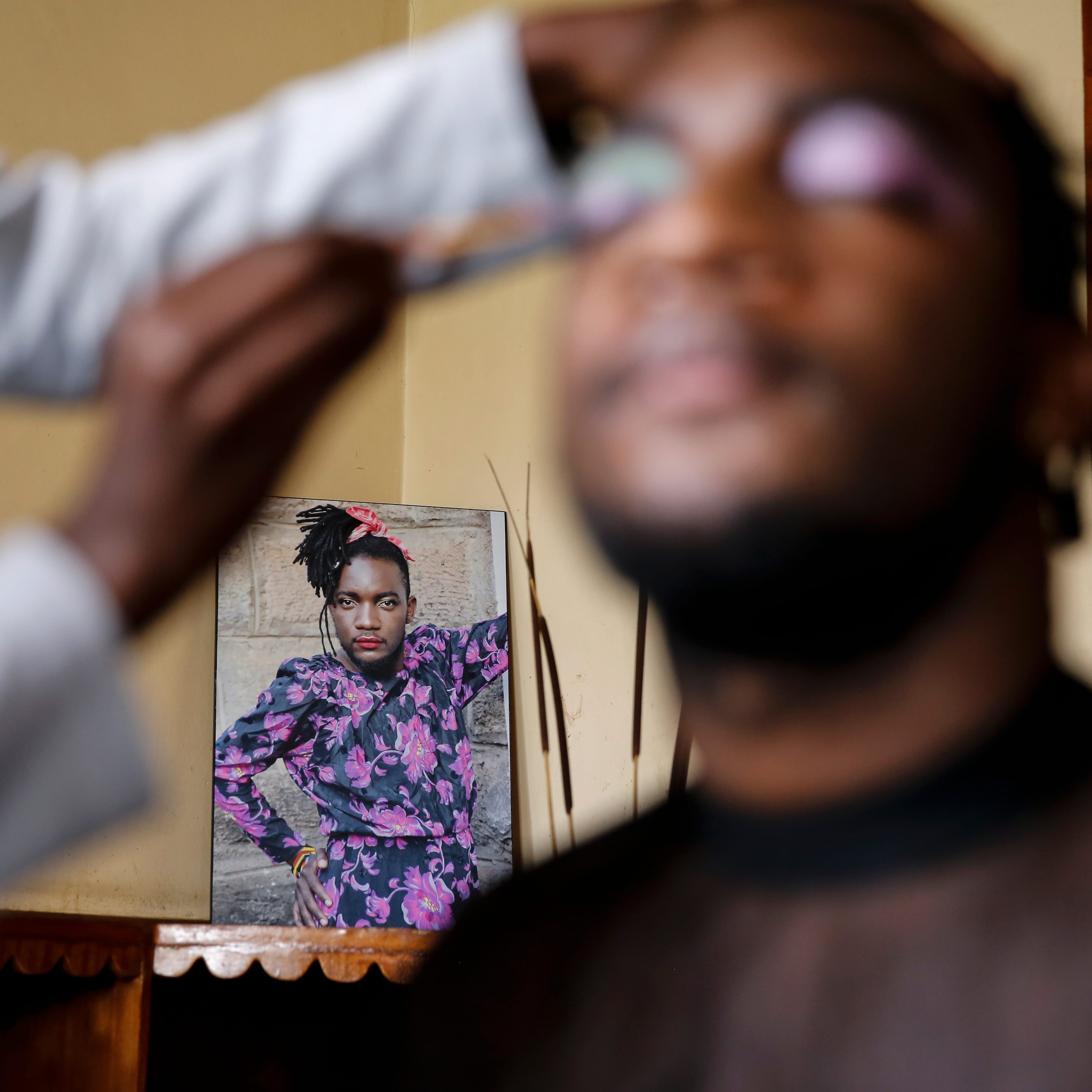 In this photo taken Thursday, June 11, 2020, Raymond Brian, a Ugandan refugee who is gender non-conforming,  has makeup done in a house at a house that serves as a shelter for LGBT refugees in Nairobi, Kenya. "People feel comfortable here because it's not far from the family setup," Brian said. "We use family therapy to help each other overcome the trauma from our pasts."