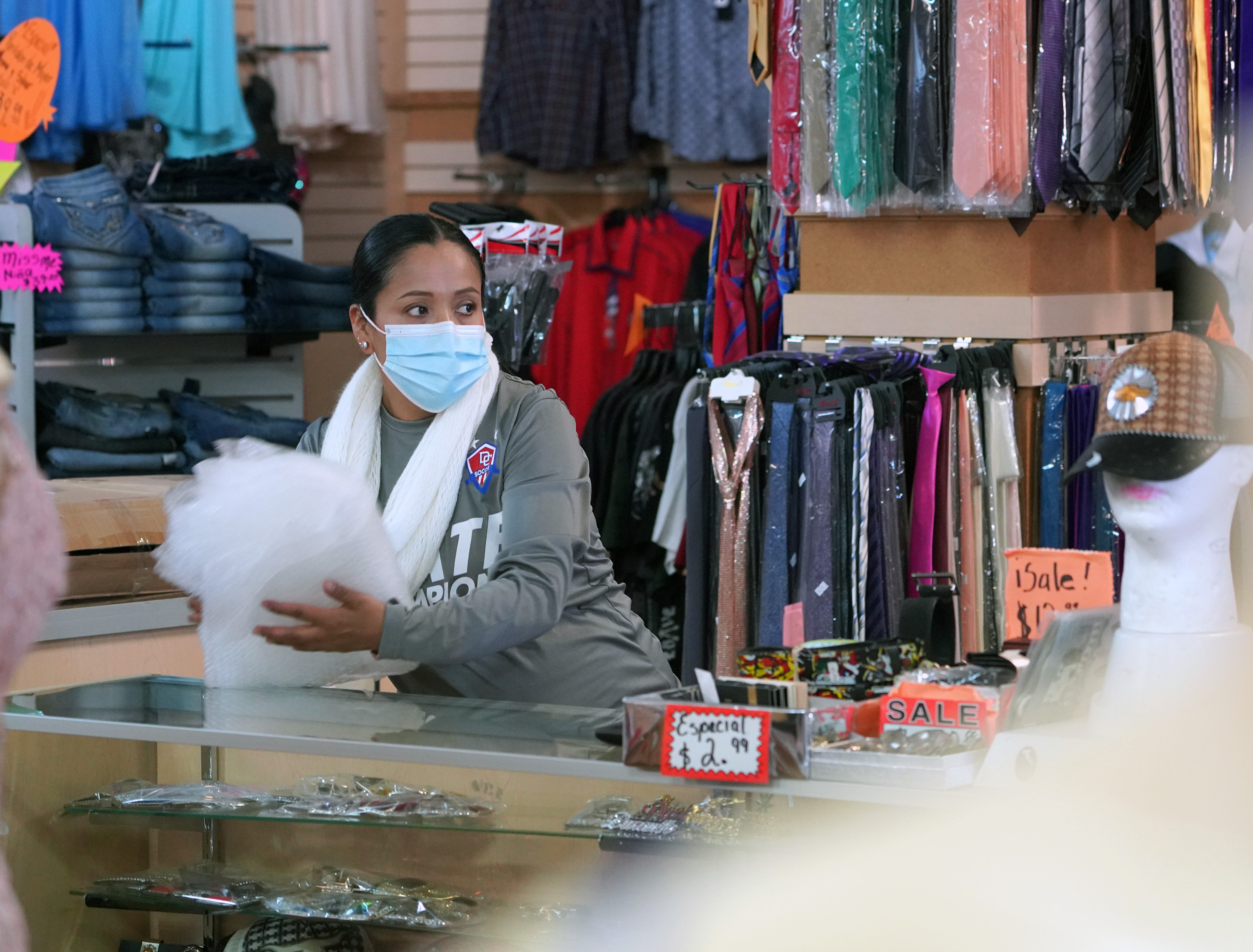 Esthela Cisneros works at Ensueño Boutique in downtown Dodge City, Kan. Her boss, Andres Lima, said he's required staff and customers to wear masks inside the store for months.