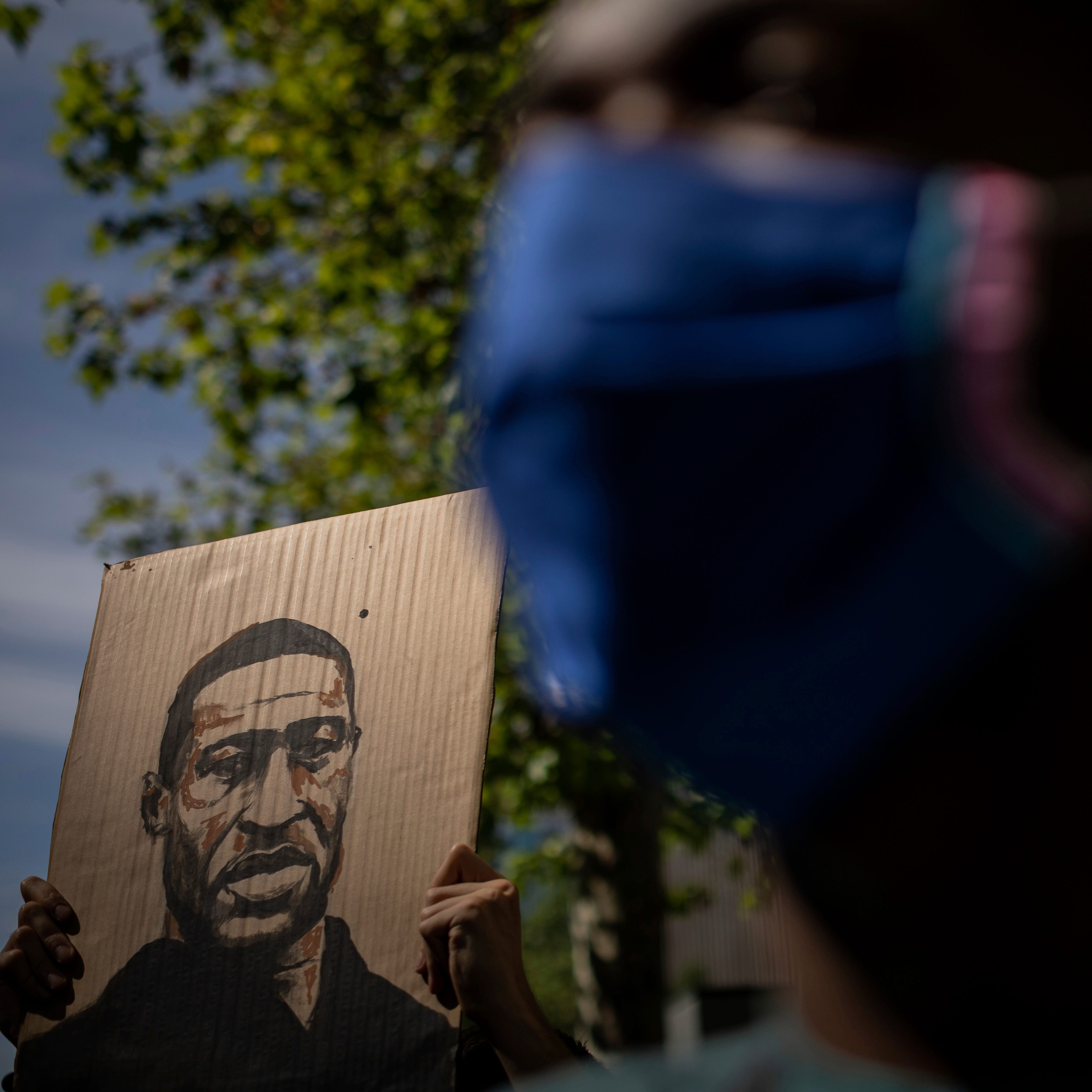 A demonstrator holds a George Floyd placard in front the American embassy in Madrid, Spain, Sunday, June 7, 2020 during a demonstration over the death of George Floyd and victims of racial injustice. 