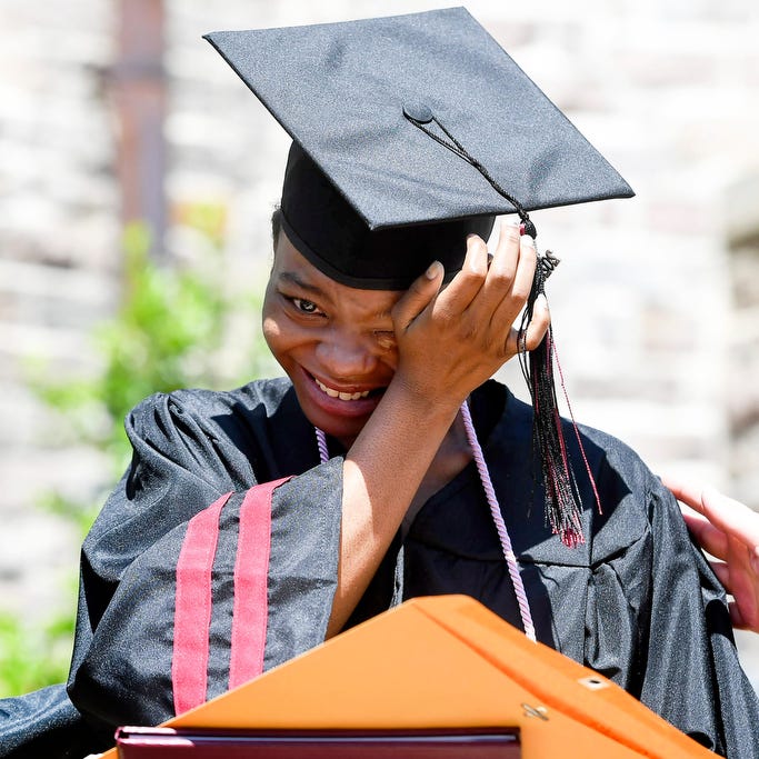 Raginder McCoy wipes tears from her eyes while Asheville High School staff can't help but reach out to her as she receives her diploma without her classmates May 30, 2020, in Asheville, North Carolina.
