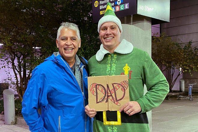 Doug Henning, right, who was adopted as a baby, poses with his biological father after meeting face to face for the first time on Nov. 24, 2020, at Logan International Airport in Boston. Henning, of Eliot, Maine, wore a costume like the one actor Will Ferrell's character wore in the movie "Elf" and he broke into the same awkward song from the movie while meeting his father.   [(Rebecca Taylor Henning via AP])