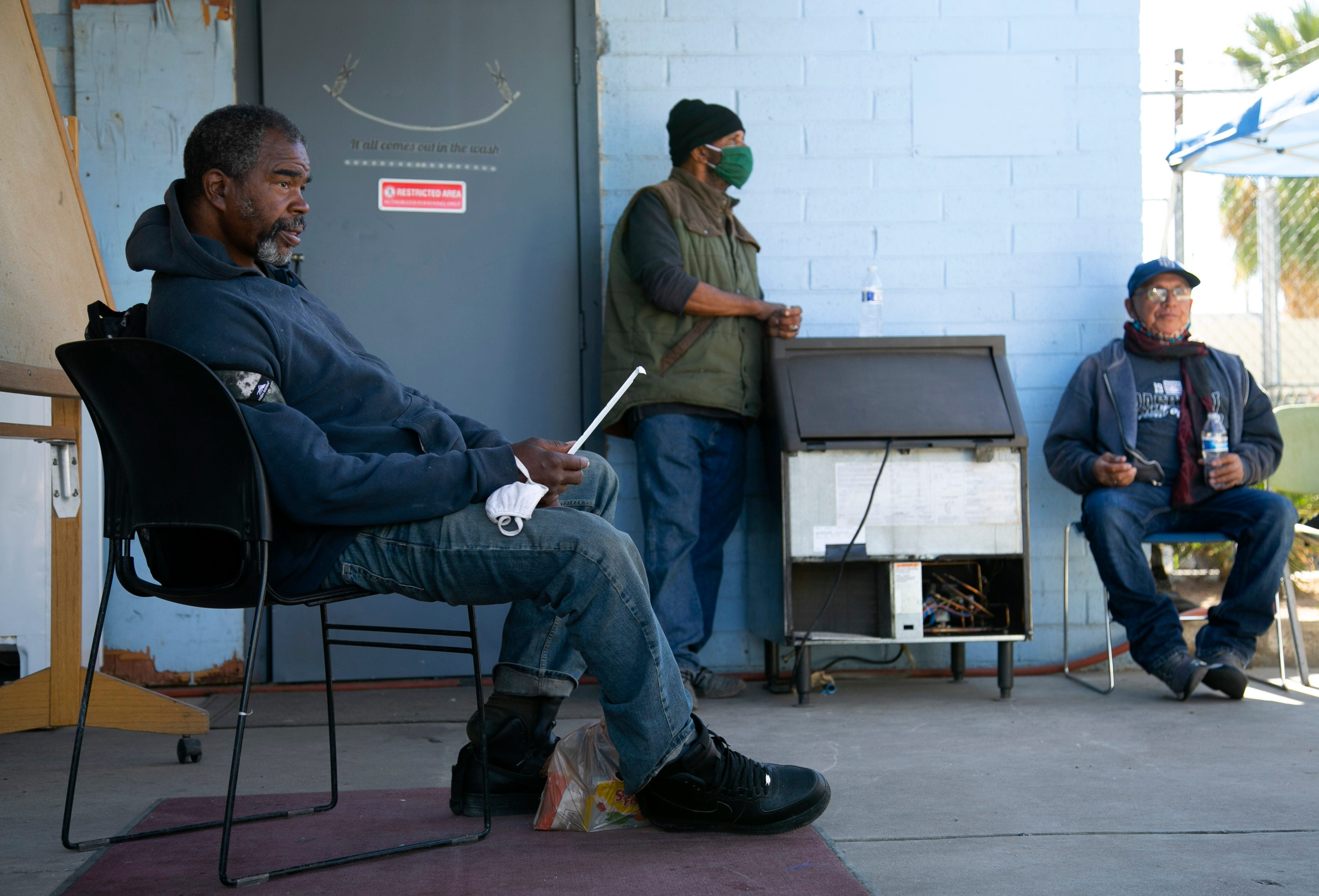 Kyle Holloway, 57 (from left), Zachery Walker, 60, and Henry Aguilar, 62, rest at the Justa Cente in Phoenix on Dec. 9, 2020.