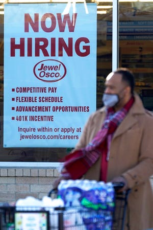 A shopper exits a grocery store as a hiring sign is seen in Deerfield, Ill., Thursday, Dec. 4, 2020. U.S employers added about 245,000 jobs in November, as companies scaled back their hiring as the viral pandemic accelerates across the country. (AP Photo/Nam Y. Huh)