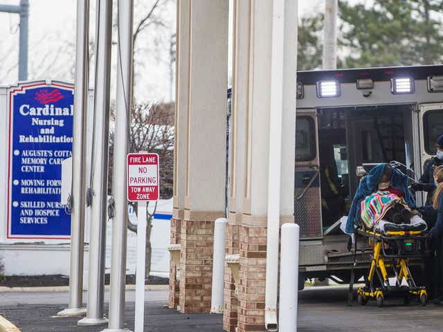 A person is loaded into an ambulance outside Cardinal Nursing and Rehabilitation on Tuesday, April 14, 2020, in South Bend, Ind.