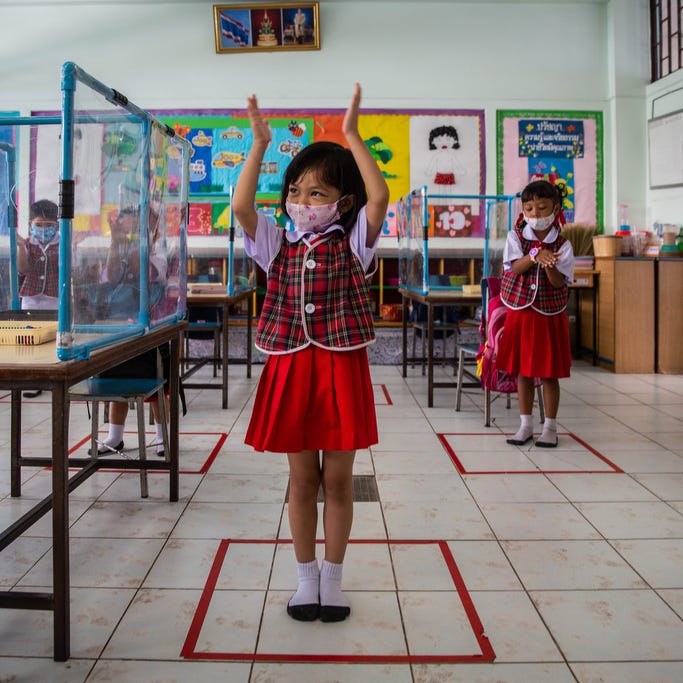 Thai kindergarteners wear face masks and stand in square outlines used for social distancing as they sing a song about washing their hands at the Wat Khlong Toey School on August 10, 2020 in Bangkok, Thailand.