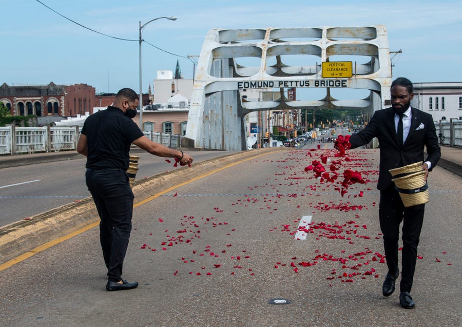 Marcus Sharp, left, and Justin Mayes lay rose petals on the path of civil rights icon and U.S. Congressman John Lewis's casket on the Edmund Pettus Bridge in Selma, Ala., on Saturday, July 26, 2020.