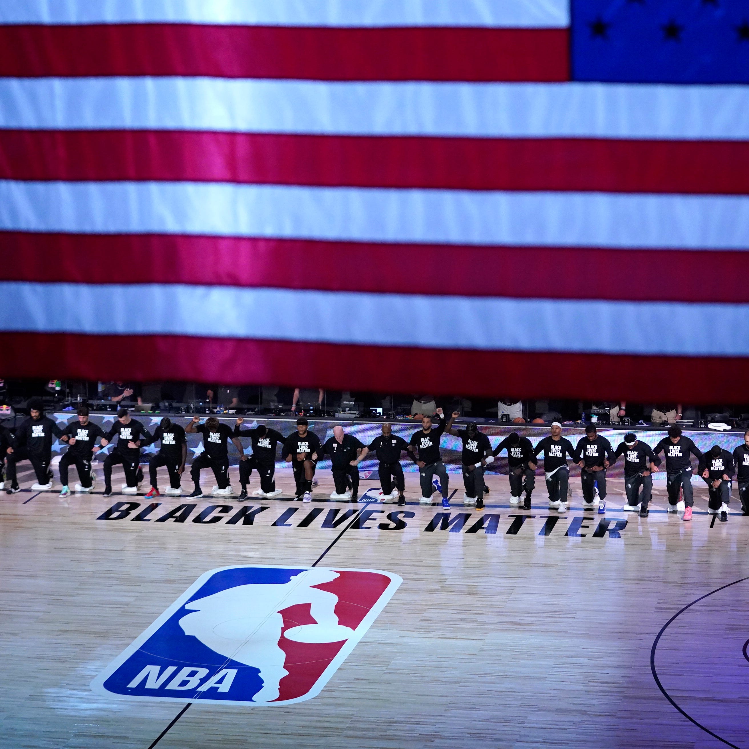Members of the Orlando Magic and Brooklyn Nets kneel around a Black Lives Matter logo during the national anthem before the start of an NBA basketball game on July 31, 2020. 