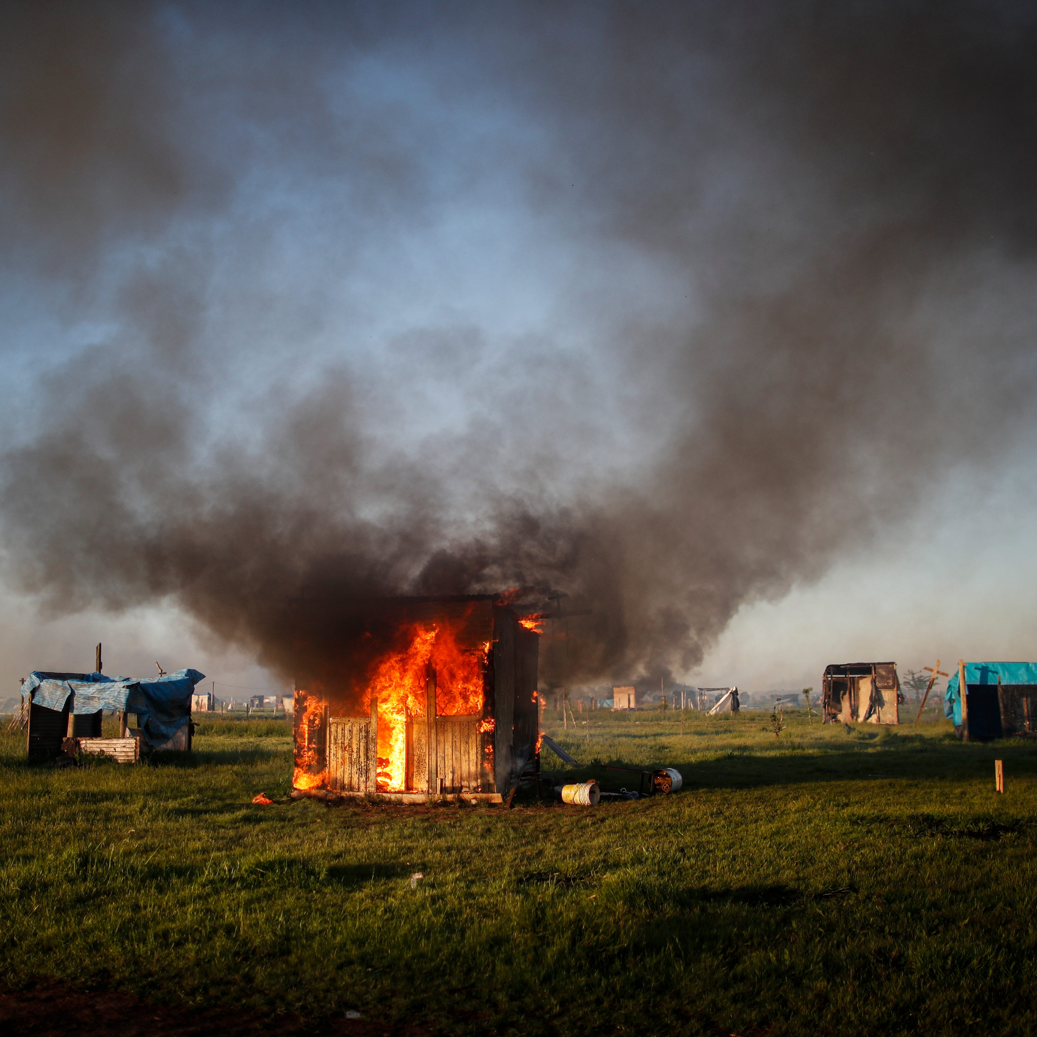 A shack home burns as people are evicted from a squatters camp by police in Guernica, Buenos Aires province, Argentina, Thursday, Oct. 29, 2020. A court ordered the eviction of families who have been squatting at the camp since July, but the families say they have nowhere to go amid the COVID-19 pandemic. 